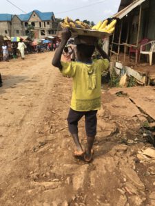 Un enfant sur la route à Kamituga Sud - Kivu portant banane sur sa tête pour vente